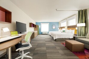 Une chambre d’hôtel équipée d’un bureau, d’une chaise, d’un lit, d’une table de chevet, d’une lampe et d’un téléviseur.