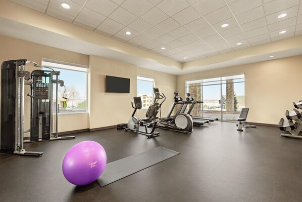 Une salle de sport équipée de matériel d’exercice, dotée d’une grande fenêtre et comprenant un ballon d’exercice violet.