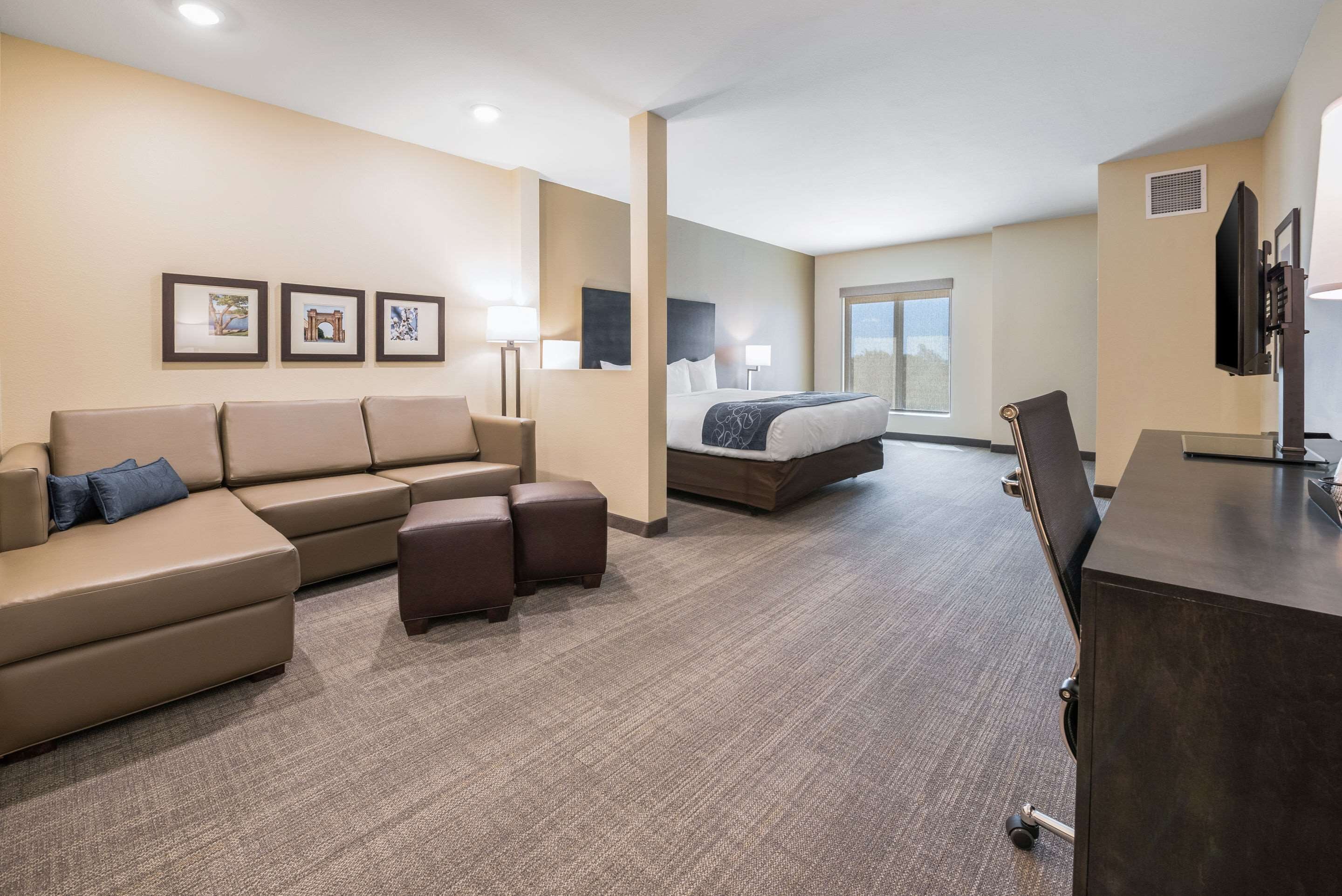 A hotel room with a large sofa, a bed, a desk, and a television.
