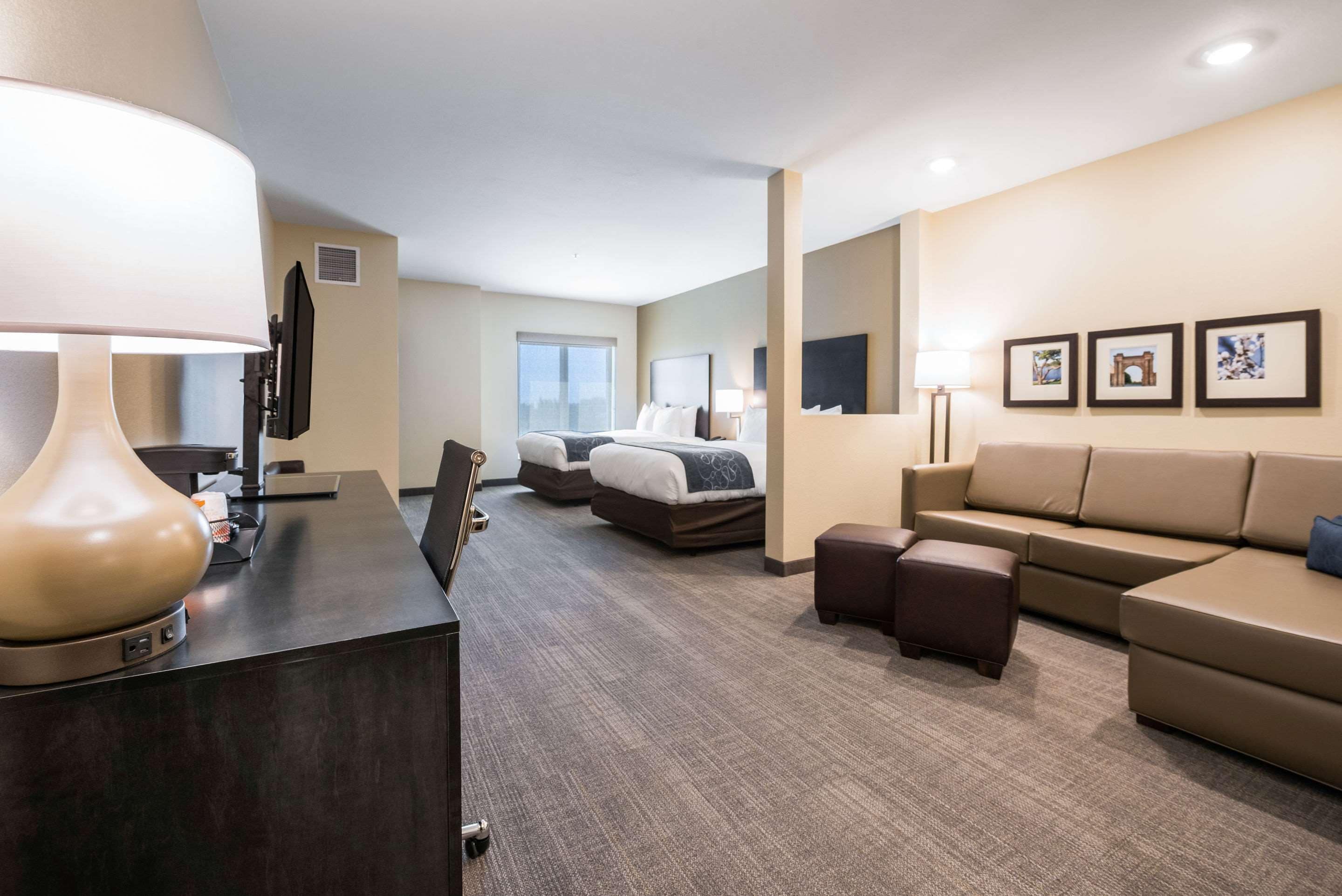 Una habitación de hotel con un escritorio, dos camas, un sofá y un televisor.