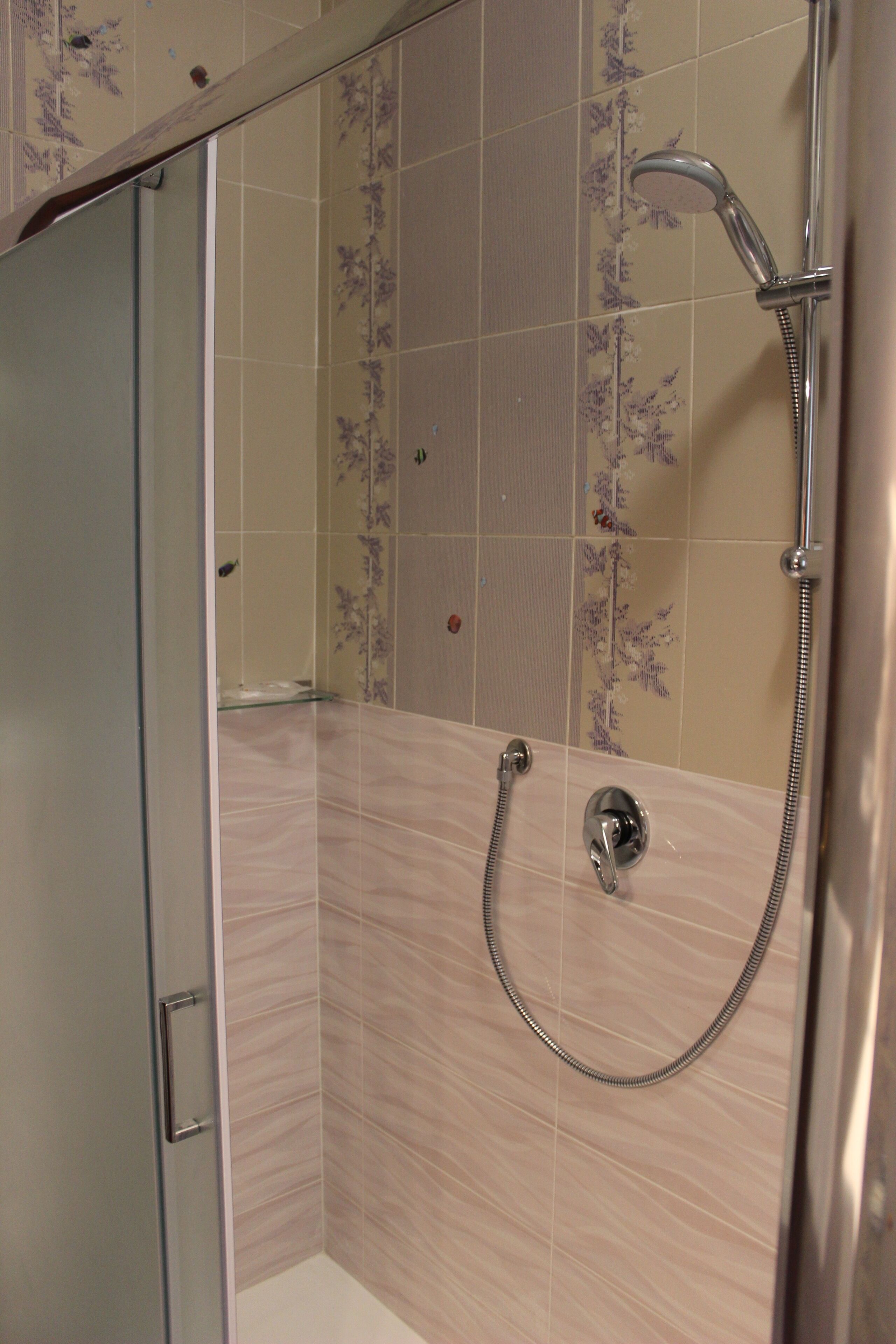 A shower with a handheld showerhead and a wall-mounted faucet.