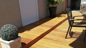A wooden deck with a planter, a potted plant, and a chair.