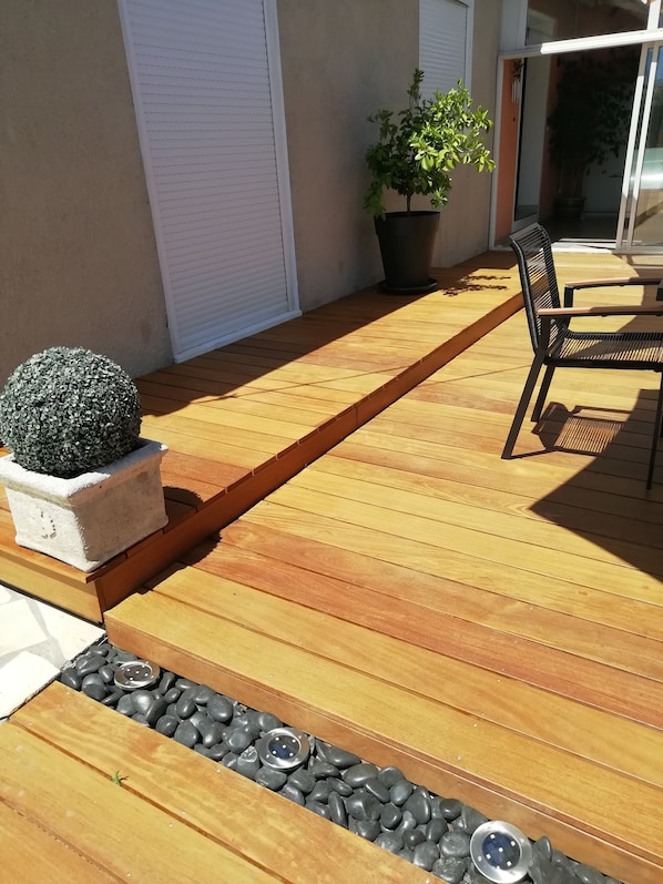 A wooden deck with a planter, a potted plant, and a chair.