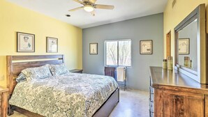 Een slaapkamer met een bed, een plafondventilator, een dressoir en ingelijste foto's aan de muur.