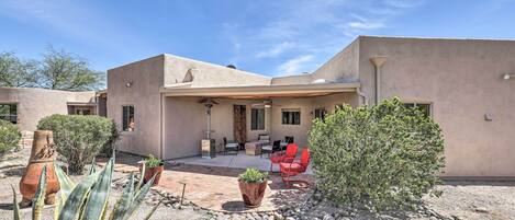 Una casa moderna con un patio, mobiliario exterior y cactus.