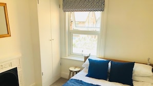 Une chambre à coucher avec un lit, une fenêtre, une cheminée et une porte.