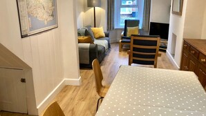 Un salon chaleureux avec un canapé, des fauteuils, une table à manger et une carte accrochée au mur.