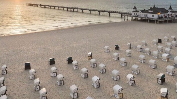 A beach with rows of white beach huts and a pier extending into the water. - Hus Günter - Apartment Maritim (Seebad Ahlbeck)