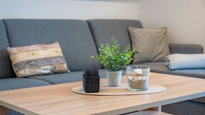 A wooden table with a potted plant, a glass container, and a small black bag on a woven placemat. - Hus Günter - Apartment Maritim (Seebad Ahlbeck)