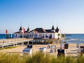 A beachfront hotel with a pier, beachside seating, and flags. - Hus Günter - Apartment Nautilus (Seebad Ahlbeck)