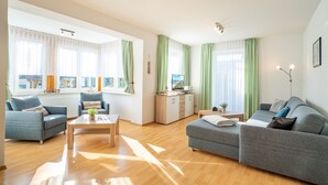 A spacious living room with a sofa, a coffee table, and a TV stand. - Hus Günter - Apartment Nautilus (Seebad Ahlbeck)
