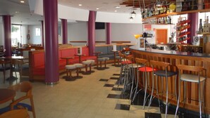 A bar area with stools, a counter, and a variety of bottles. - Hotel Fenals Garden (Lloret de Mar)