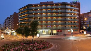 A multi-story hotel with balconies, a visible entrance, and a well-lit facade. - Hotel Fenals Garden (Lloret de Mar)