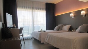 A hotel room with two beds, a desk with a chair, a TV, and a window with curtains. - Hotel Fenals Garden (Lloret de Mar)