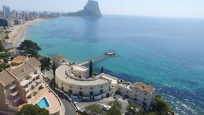 A coastal hotel with a round building, a pool, and a view of the sea and a prominent rock formation. - Apartamento Anfiteatro by Costa CarpeDiem (Calpe)