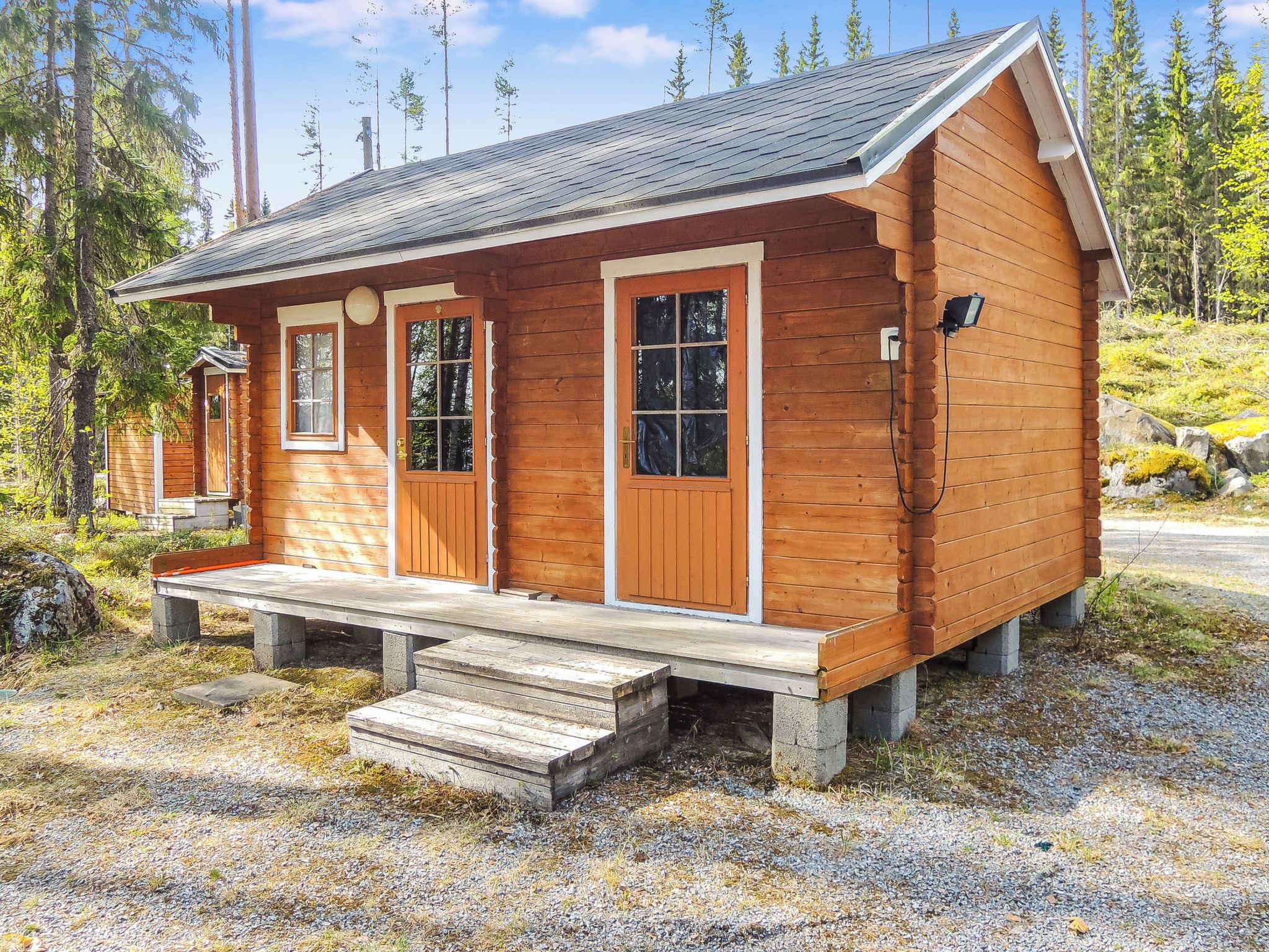 A small wooden cabin with a porch, two doors, and a window.