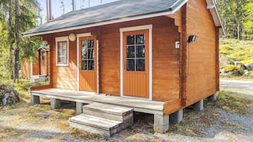 A small wooden cabin with a porch, two doors, and a window.