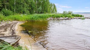 A riverbank with a wooden boat, surrounded by greenery and trees.