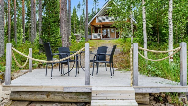 A wooden deck with outdoor seating and a rope barrier leading to a lodge.