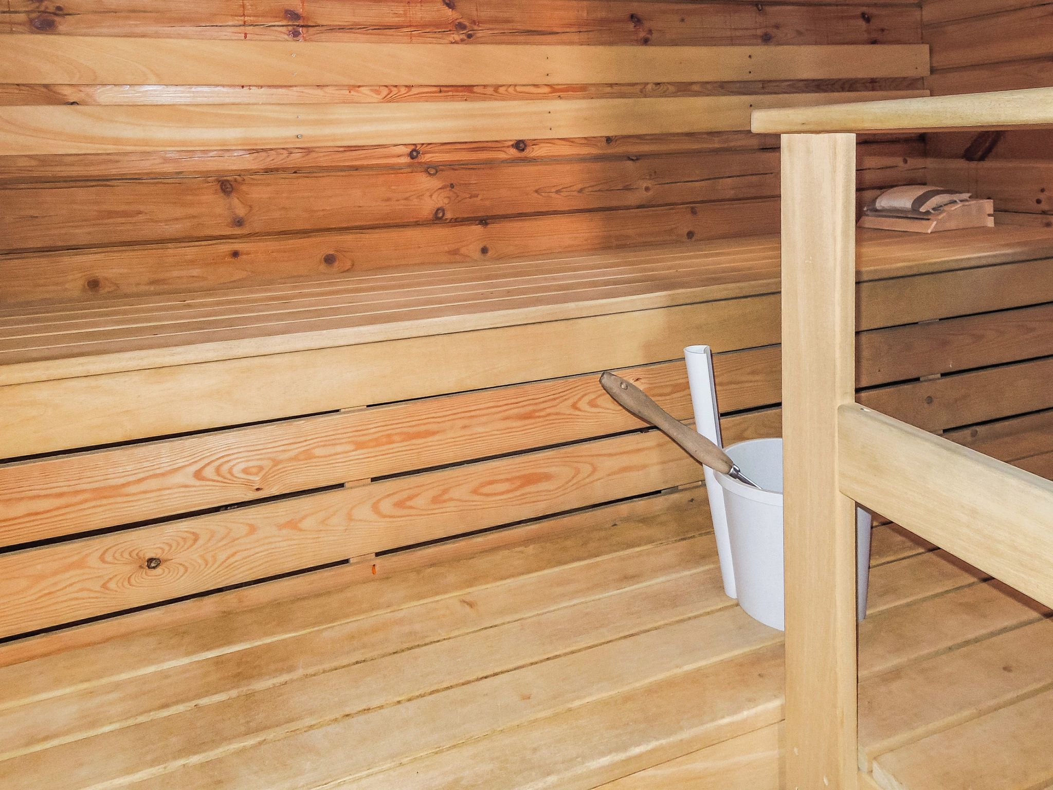 Una sauna in legno con una panca e un catino.
