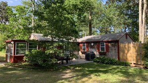 Eine kleine Holzhütte mit Veranda, Grill und einer Uhr an der Wand.