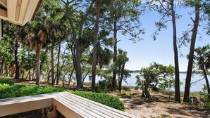 A wooden deck with a bench, surrounded by trees and a view of a lake. - 3 Bdrm 2 Bath Waterfront Villa on Dataw with Dock, Bikes, Pool and Beach Pass!  (St Helena Island)