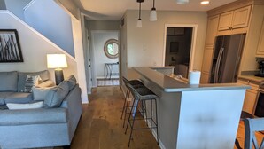 A modern kitchen with a central island, bar stools, and a dining table. - 3 Bdrm 2 Bath Waterfront Villa on Dataw with Dock, Bikes, Pool and Beach Pass!  (St Helena Island)