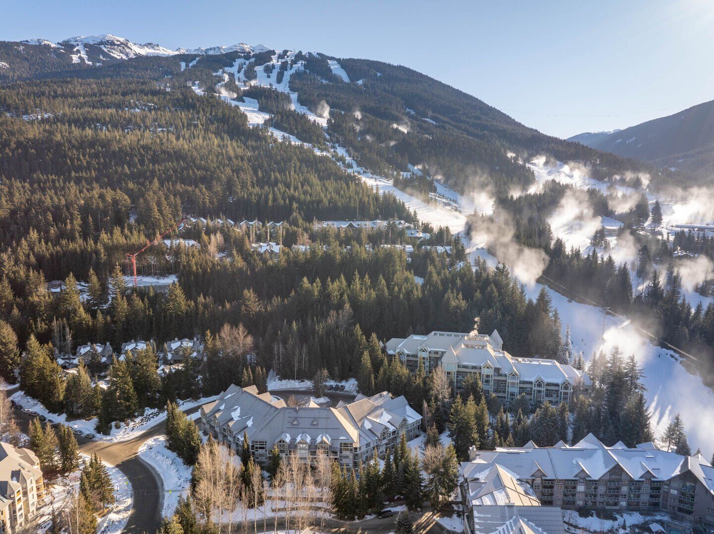 A resort with multiple buildings, a ski slope, and a mountain backdrop.