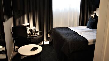 Una habitación de hotel con una cama, una silla, una mesita y un televisor.
