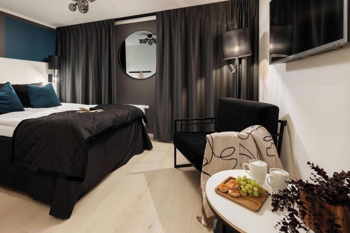 Une chambre d’hôtel moderne équipée d’un lit, d’une chaise, d’une table avec un petit-déjeuner et d’une télévision.