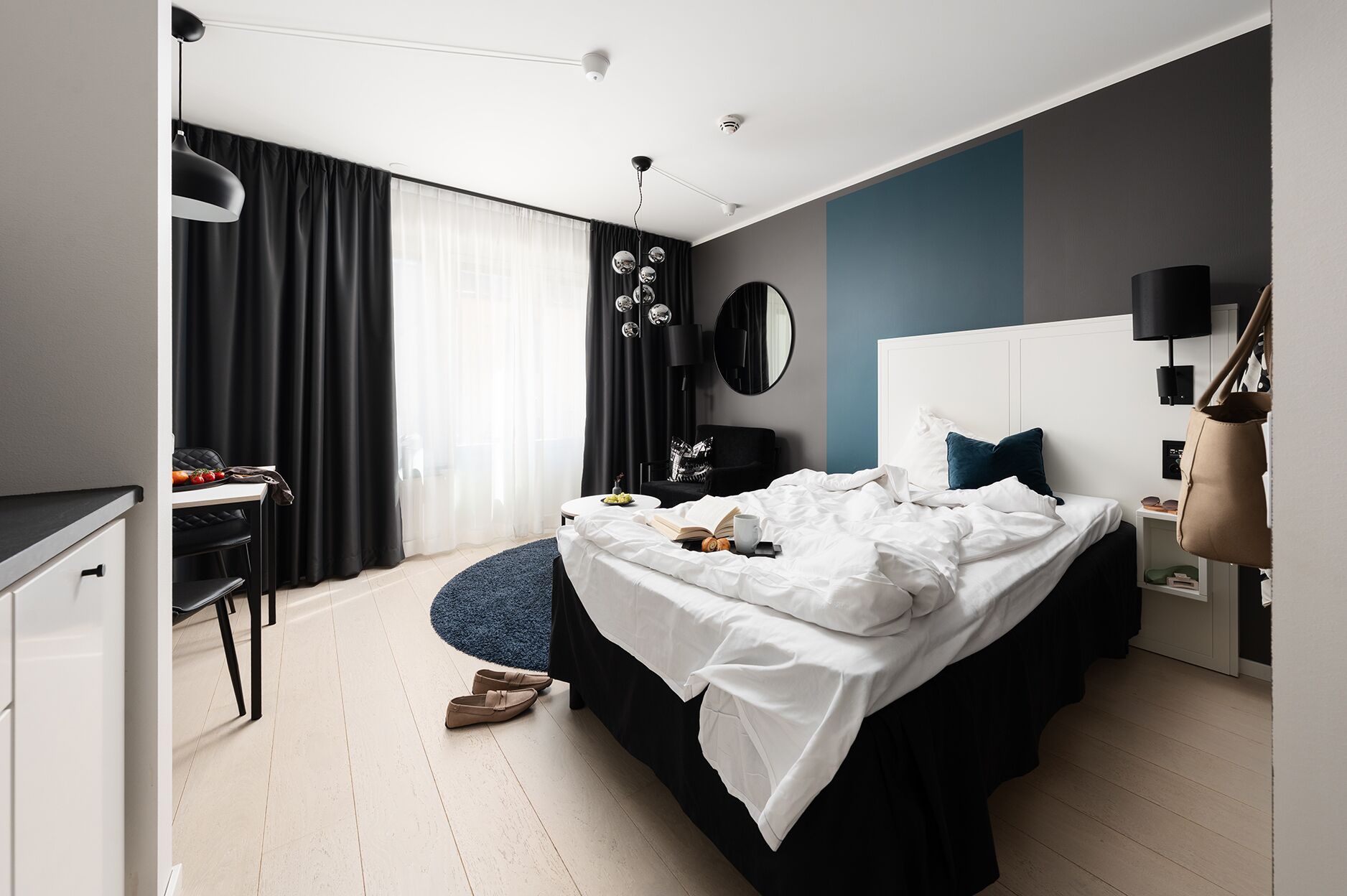 A modern bedroom with a bed, bedside table, and a desk with a chair.