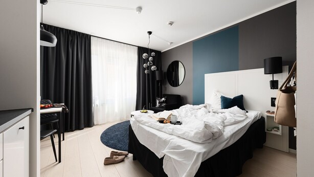 A modern bedroom with a bed, bedside table, and a desk with a chair.