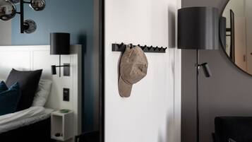 Un dormitorio con cama, un perchero de pared, una lámpara de pie y un espejo.