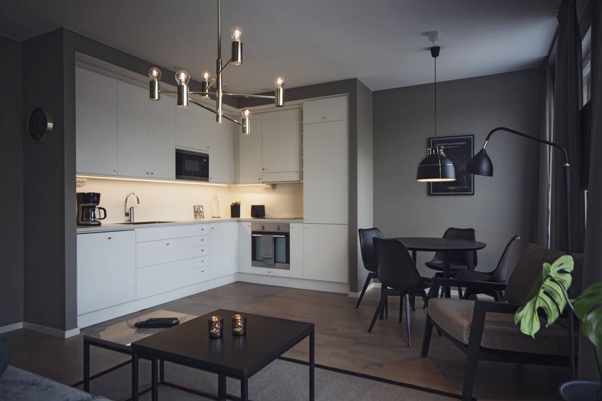 Une cuisine moderne avec des meubles blancs, un coin repas comprenant une table et des chaises, et un luminaire suspendu.