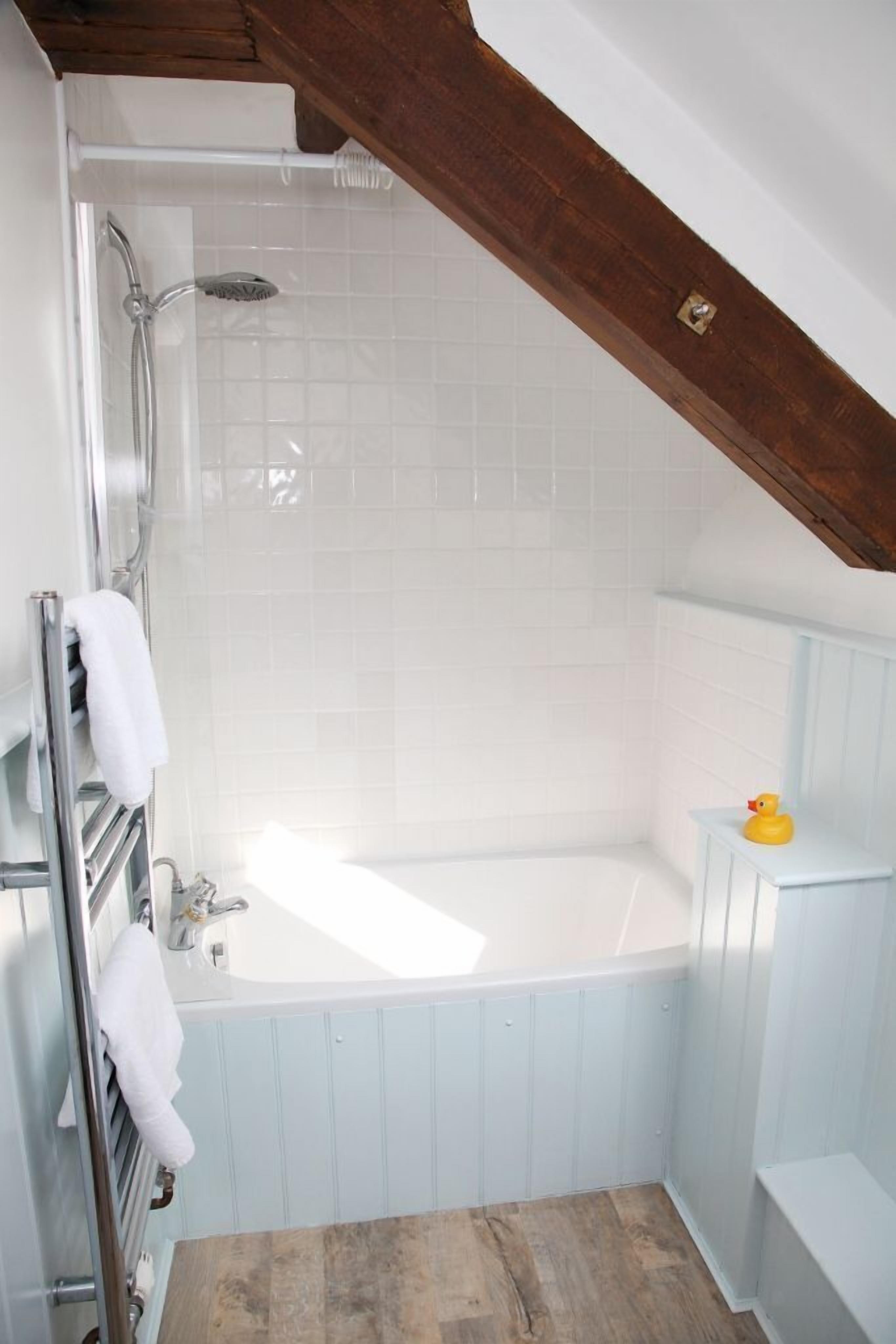A bathroom with a bathtub, a shower, and a wooden ceiling.