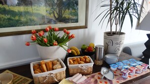 Un bufé de desayuno con pan, bollería, queso, jamón y yogur.