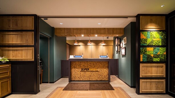 Un área de recepción con un mostrador de madera, una mesa de registro y una pared con un mosaico verde y amarillo.