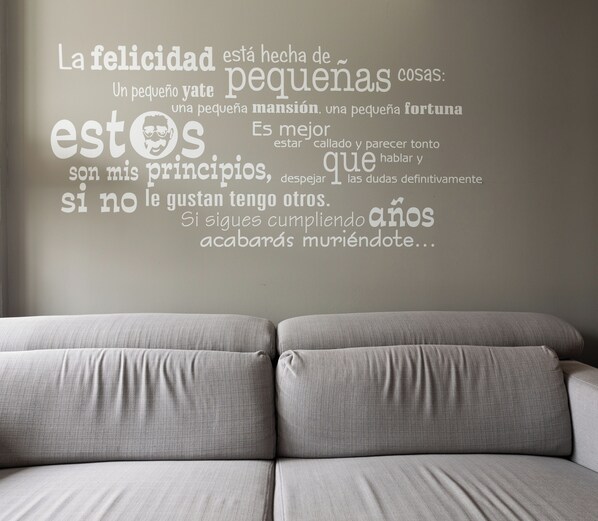 Un sofá gris en una habitación con una frase motivadora en la pared.
