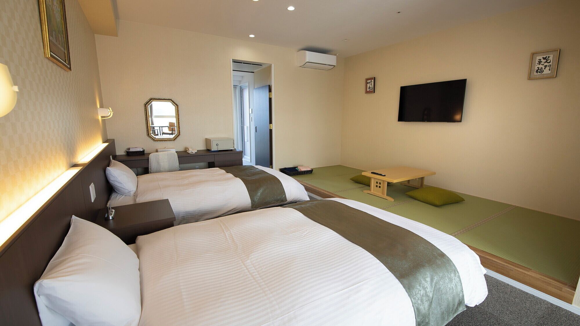 Una habitación de hotel con dos camas, un escritorio, una silla, un televisor y una mesita.