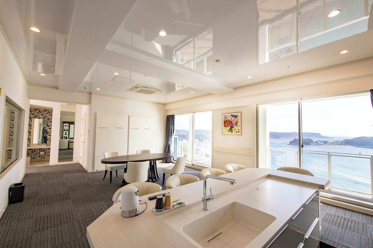 Una habitación de hotel moderna con un ventanal grande, un área de comedor y una cocina.
