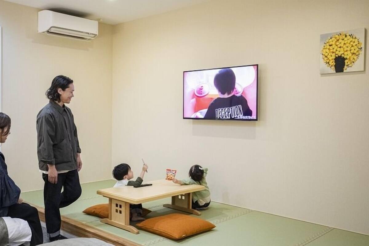 Una habitación con televisor, sofá, mesa y aire acondicionado instalado en la pared.