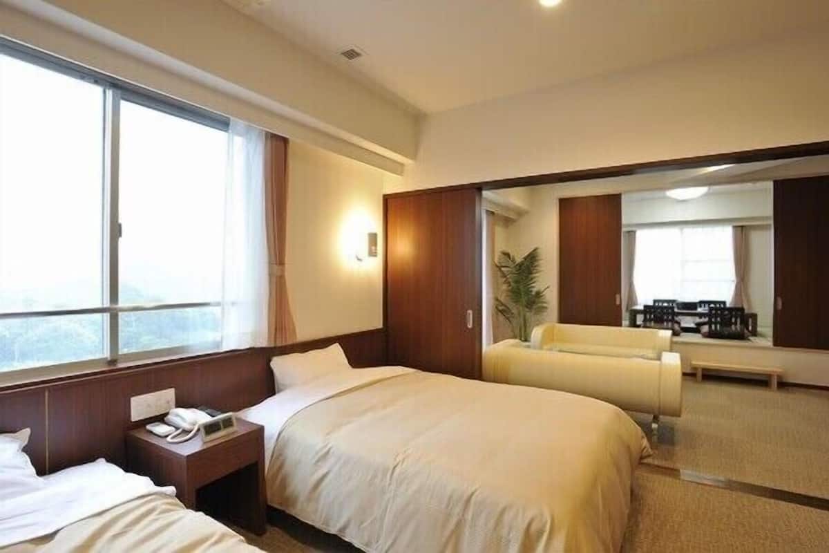 Habitación de hotel con cama, mesita de noche, lámpara y vistas a la ciudad.