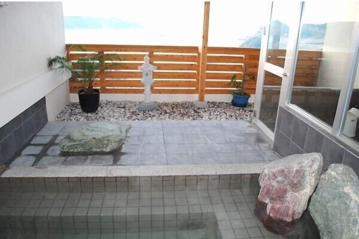 Un pequeño espacio al aire libre con un banco de piedra, plantas en macetas y una valla de madera.