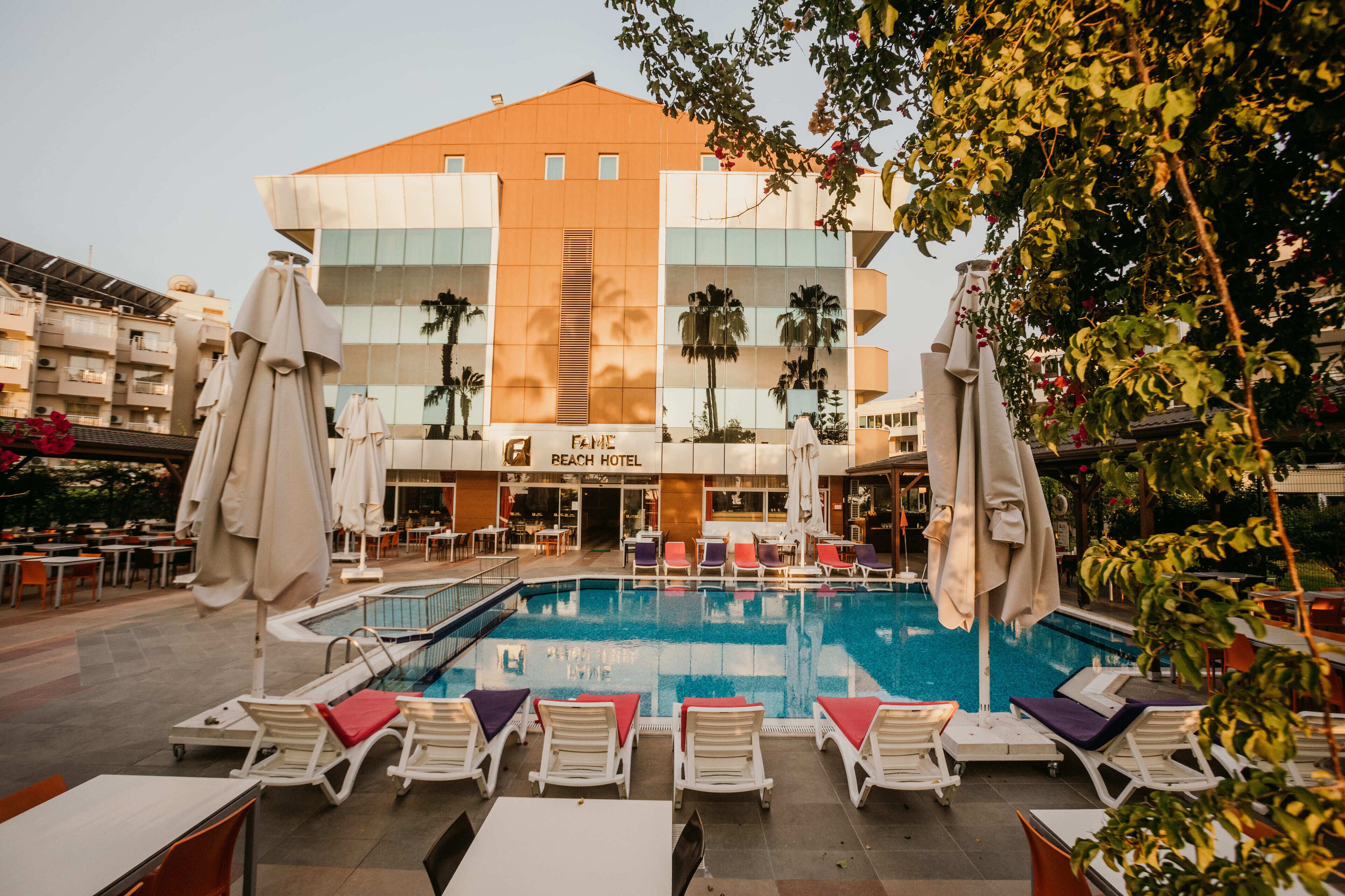 Um hotel com piscina, área de estar externa e palmeiras.