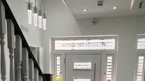 Un intérieur moderne avec un escalier, un comptoir d’accueil et une enseigne au-dessus de la porte.