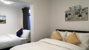 Une chambre d’hôtel avec deux lits, un tableau au mur et une fenêtre avec des rideaux.