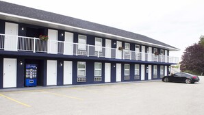 Et motel med række af lavtliggende værelser, parkeringsplads og en Pepsi-automat.