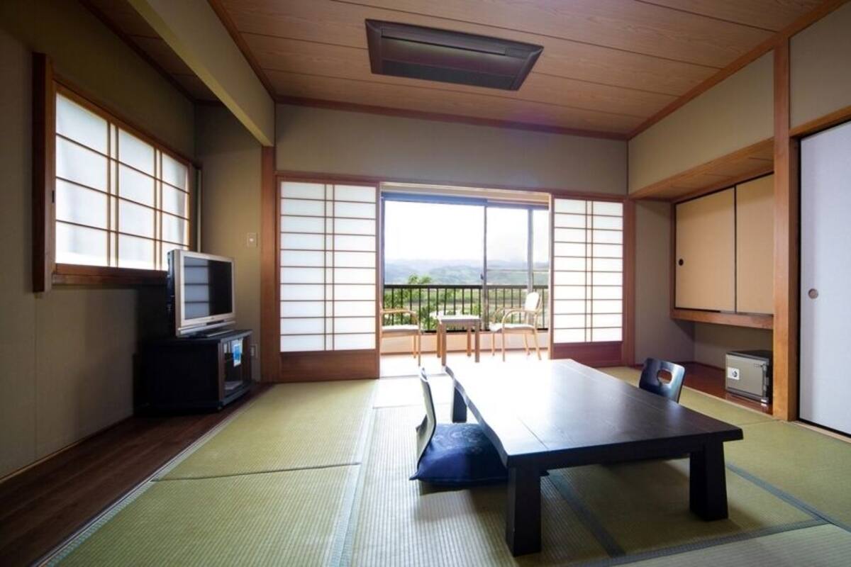 Um quarto japonês tradicional com tatames, uma mesa baixa e portas corrediças.