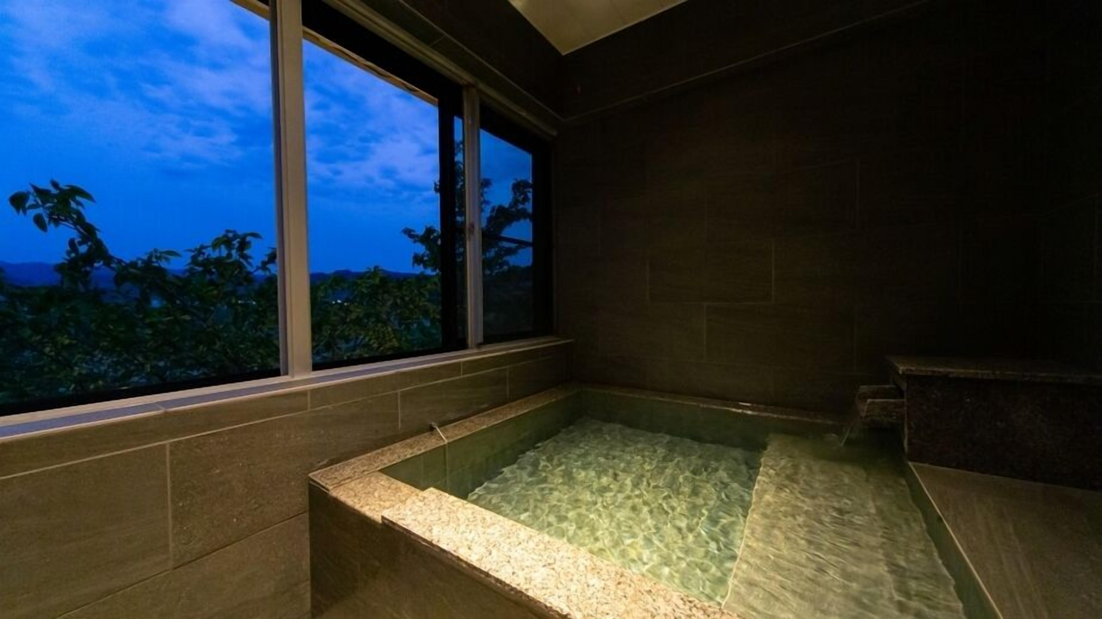 Ein Spa-Raum mit großem Fenster, einer Whirlwanne und Blick auf Bäume.