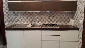 A kitchen with a sink, stove, and white cabinets. - Beach house with large garden (Seaside Paradise Vasto) (Vasto)
